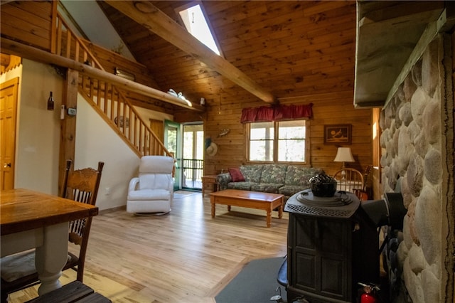 living room featuring hardwood / wood-style flooring, beam ceiling, high vaulted ceiling, wood walls, and a skylight