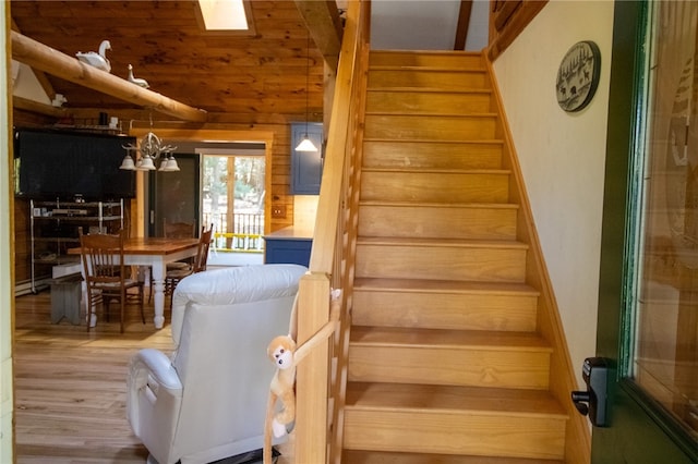 stairs with a baseboard heating unit, wooden walls, vaulted ceiling, and hardwood / wood-style floors