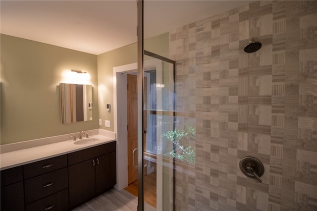 bathroom featuring tiled shower, wood-type flooring, and vanity