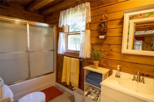 full bathroom with hardwood / wood-style flooring, wooden walls, enclosed tub / shower combo, vanity, and toilet