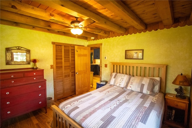 bedroom featuring dark wood-type flooring, beam ceiling, a closet, wood ceiling, and ceiling fan