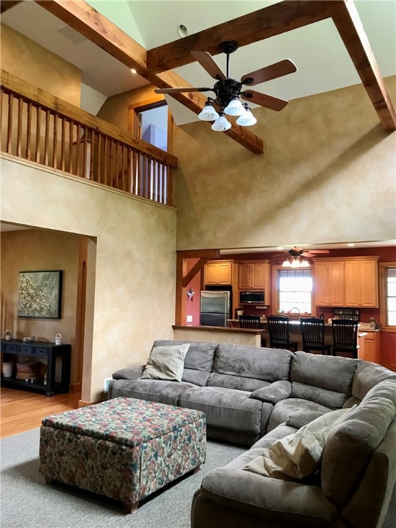 living room with high vaulted ceiling, beamed ceiling, ceiling fan, and light hardwood / wood-style flooring