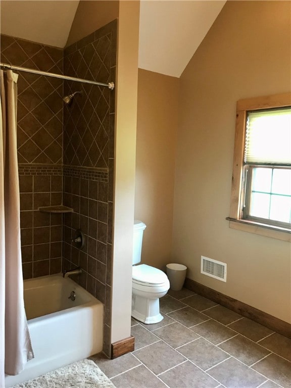 bathroom featuring tile floors, toilet, vaulted ceiling, and shower / bath combo with shower curtain