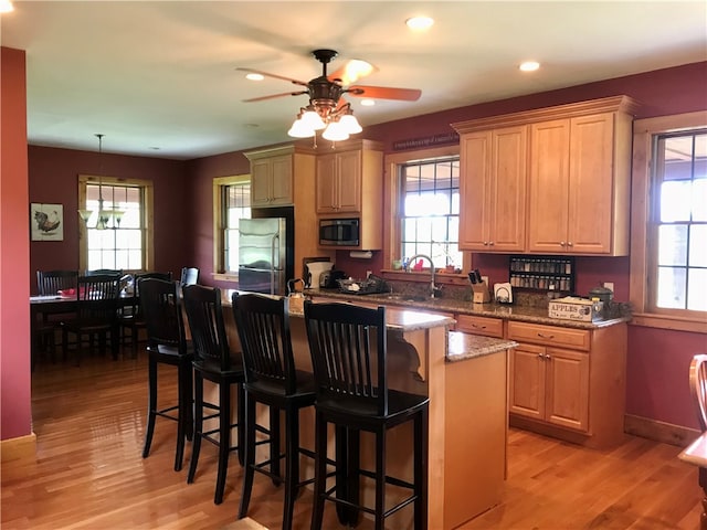 kitchen featuring stainless steel appliances, ceiling fan, a center island, and light hardwood / wood-style flooring