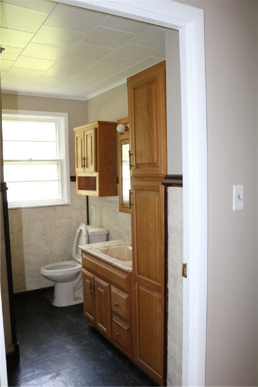 bathroom with toilet, tile patterned flooring, vanity, and tile walls