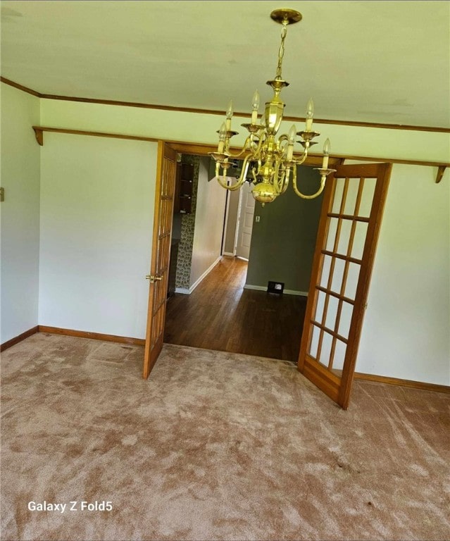 interior space featuring a chandelier, crown molding, and carpet flooring