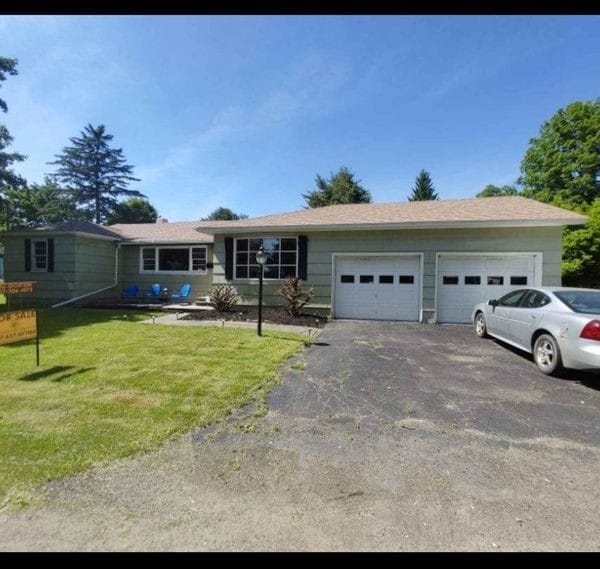 ranch-style home featuring a garage and a front lawn