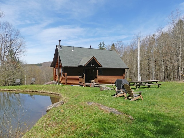 rear view of house featuring a water view and a lawn