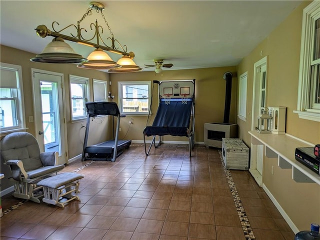 workout room with heating unit, a wood stove, dark tile patterned floors, and ceiling fan