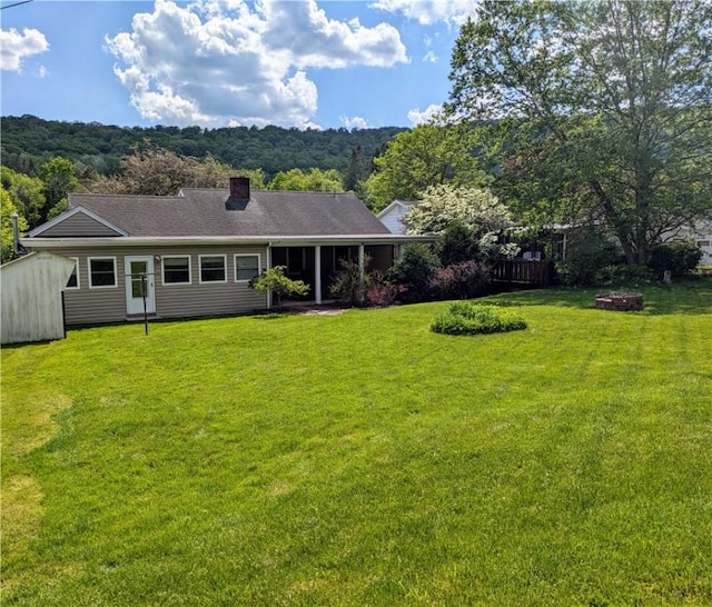 back of property with a yard and a fire pit