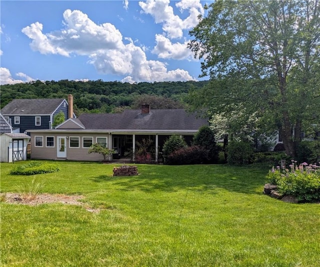 view of front of home featuring a front lawn and a storage shed