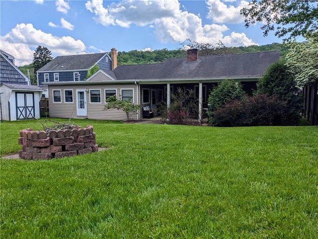 rear view of property featuring a storage unit and a yard