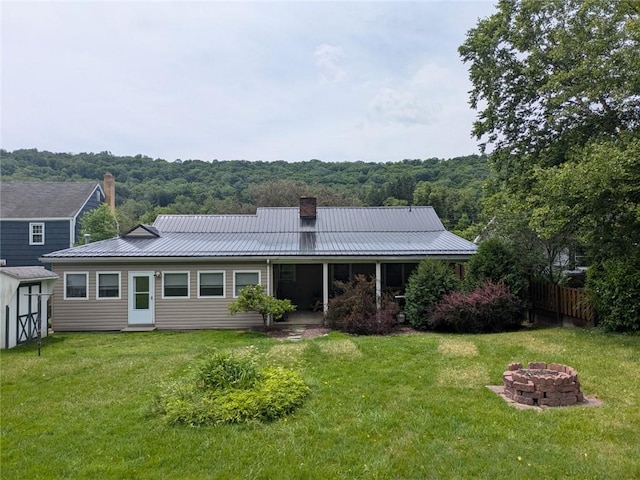 back of house featuring a fire pit and a lawn