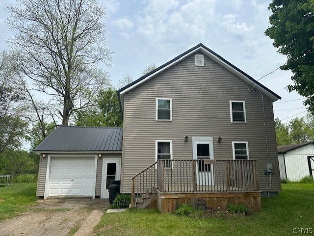 back of property with an outdoor structure, a lawn, a wooden deck, and a garage