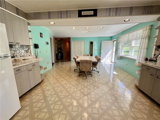 kitchen with white refrigerator, tasteful backsplash, and light stone countertops