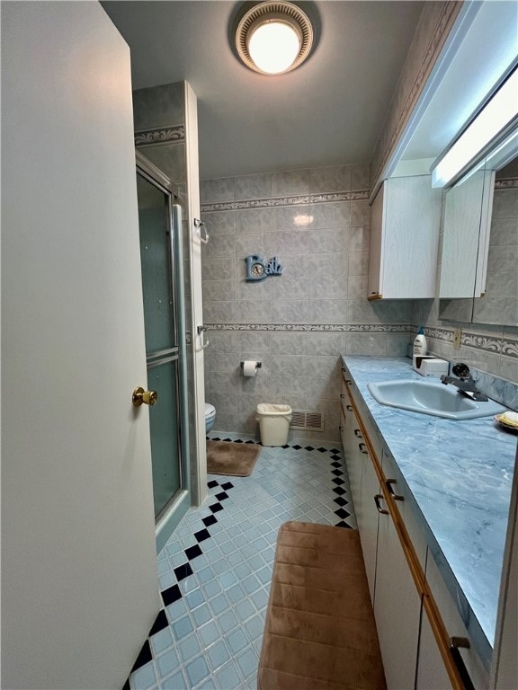 bathroom with vanity, toilet, an enclosed shower, and tile walls