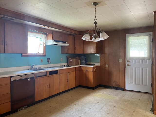 kitchen featuring sink, hanging light fixtures, an inviting chandelier, wood walls, and black appliances