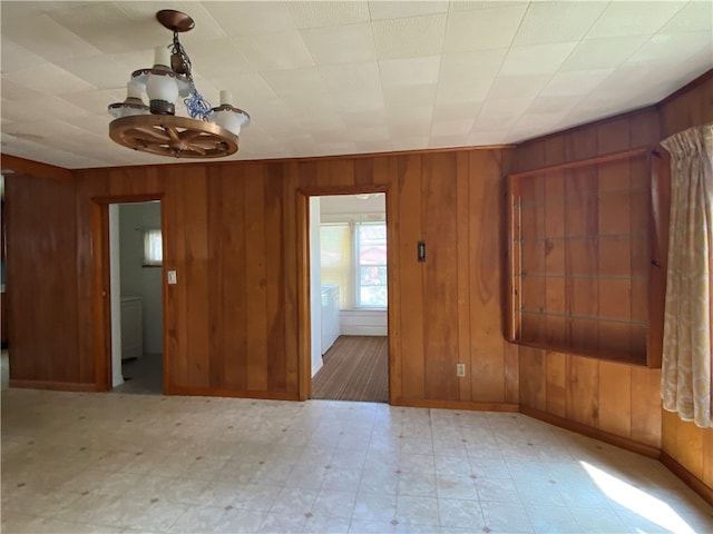 spare room with wooden walls and an inviting chandelier