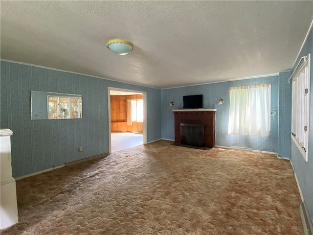 unfurnished living room with carpet floors, a textured ceiling, and a brick fireplace