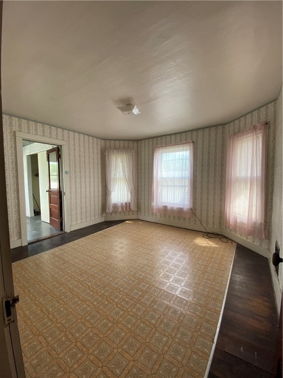 empty room with dark hardwood / wood-style floors and a wealth of natural light