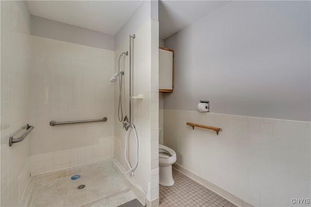 bathroom with tile walls, tile patterned floors, toilet, and a tile shower