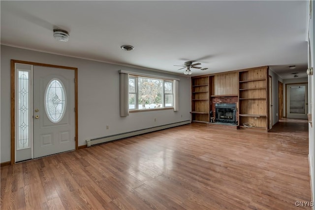 foyer entrance featuring ceiling fan, a fireplace, ornamental molding, wood-type flooring, and a baseboard radiator