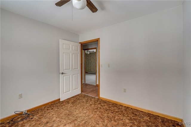 carpeted spare room featuring a baseboard radiator and ceiling fan