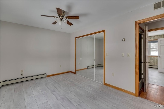 unfurnished bedroom featuring baseboard heating, a closet, and light hardwood / wood-style flooring