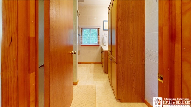 hallway with light tile floors and tile walls