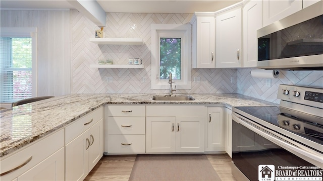 kitchen with light hardwood / wood-style floors, tasteful backsplash, stainless steel appliances, sink, and white cabinets