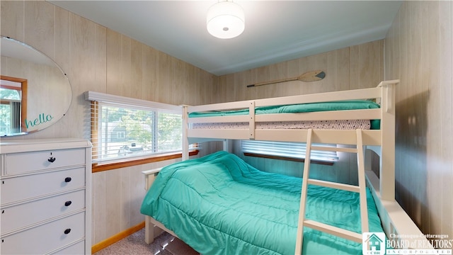 bedroom featuring wood walls and carpet