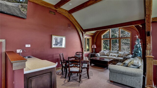 carpeted living room with sink and lofted ceiling with beams