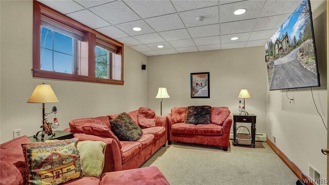 carpeted living room with a drop ceiling and a baseboard radiator