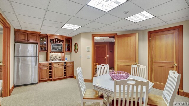 dining space featuring light carpet and a drop ceiling