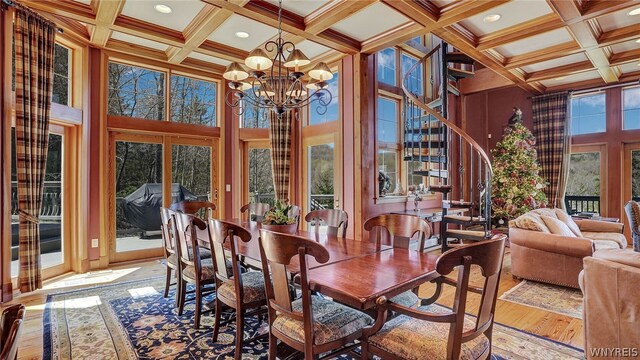 dining room with a chandelier, a high ceiling, light hardwood / wood-style floors, and beamed ceiling