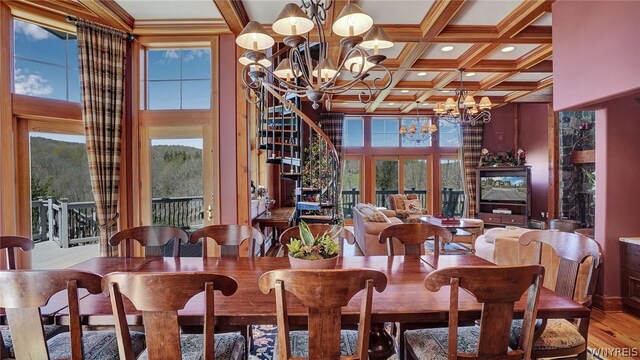 dining area with a towering ceiling, coffered ceiling, beamed ceiling, a chandelier, and hardwood / wood-style floors