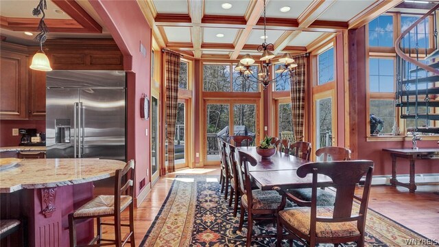 dining room featuring coffered ceiling, baseboard heating, a chandelier, beamed ceiling, and light hardwood / wood-style floors