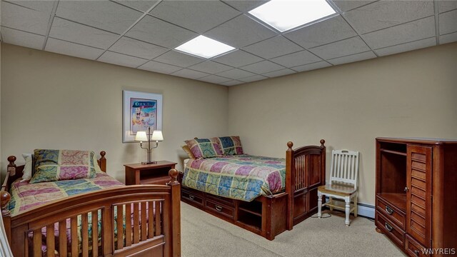 carpeted bedroom with baseboard heating and a drop ceiling