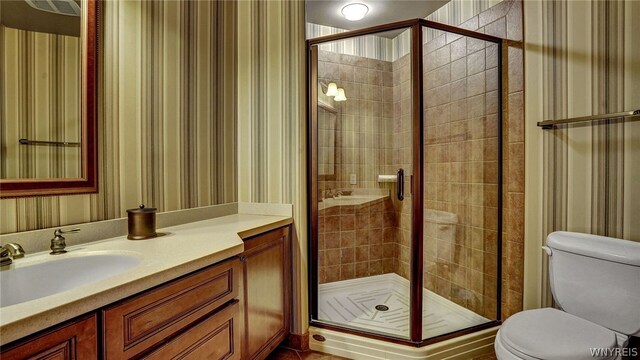 bathroom featuring vanity, toilet, and a shower with shower door