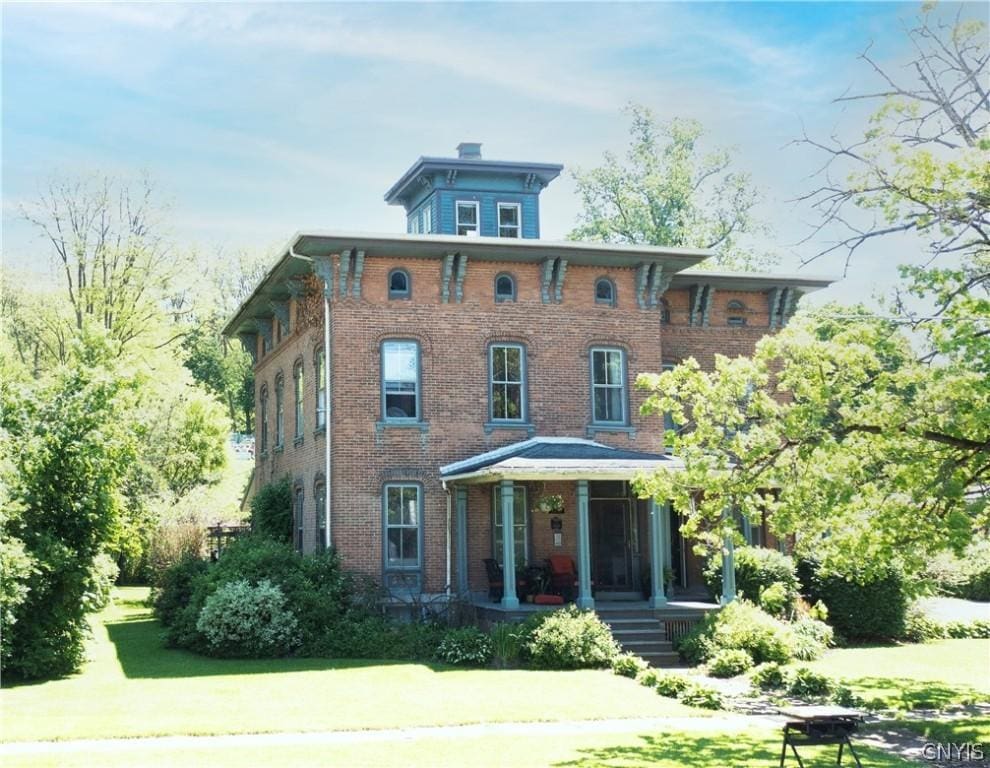 italianate house featuring a porch and a front lawn