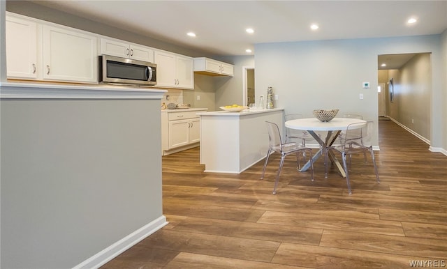 kitchen with kitchen peninsula, white cabinetry, and dark wood-type flooring