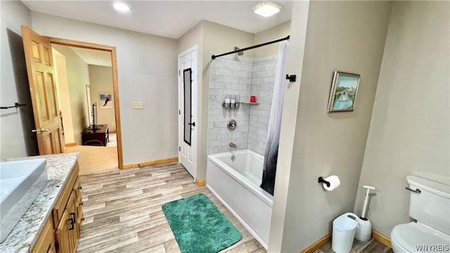 full bathroom with shower / bath combo with shower curtain, hardwood / wood-style floors, vanity, and toilet