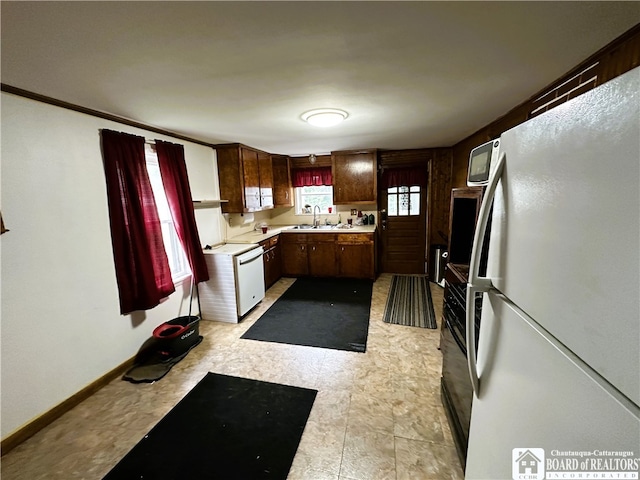 kitchen featuring white appliances, sink, light tile flooring, and plenty of natural light