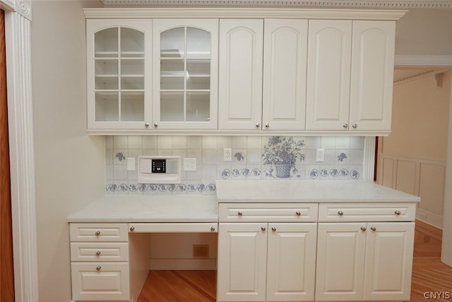 bar with tasteful backsplash, white cabinetry, and light hardwood / wood-style floors