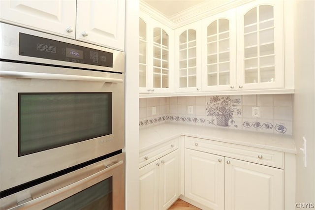 kitchen with white cabinets, double oven, and tasteful backsplash