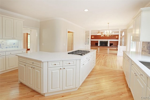 kitchen with a kitchen island, white cabinetry, hanging light fixtures, and ornamental molding