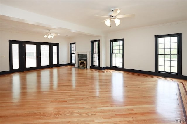 unfurnished living room featuring beamed ceiling, ceiling fan, french doors, and light hardwood / wood-style flooring