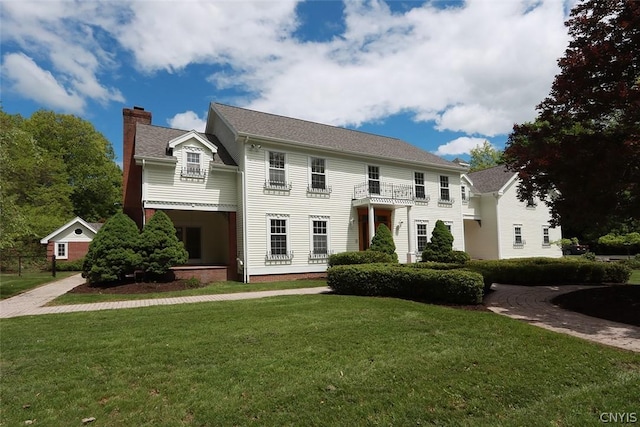 colonial inspired home featuring a front yard and a balcony