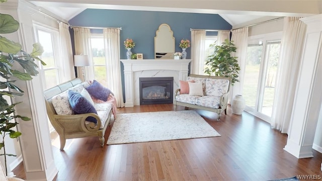 living area with a wealth of natural light, lofted ceiling, and hardwood / wood-style flooring