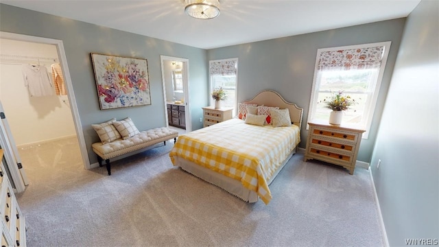 bedroom with light carpet, multiple windows, connected bathroom, and baseboards